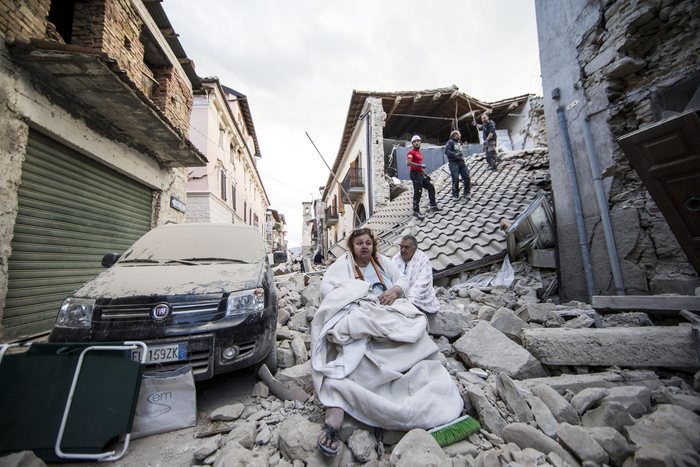 epa05603350 YEARENDER 2016 AUGUST  Residents look on as they stand on the rubble of collapsed buildings in Amatrice, central Italy, 24 August 2016, following a 6.2 magnitude earthquake, according to the United States Geological Survey (USGS), that struck at around 3:30 am local time (1:30 am GMT).  EPA/MASSIMO PERCOSSI