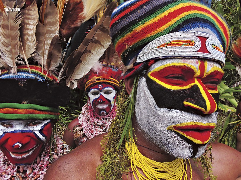 Dancers decorated with colored clay preparing for a sing sing - a cultural festival in which different tribes come together to celebrate and tell stories and legends of their ancestors by dancing, chanting and performing courting rituals.