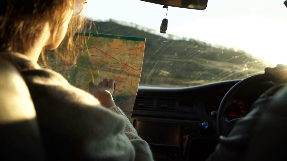 Τουρίστρια επιλέγει έντυπους χάρτες στο ταξίδι με το αυτοκίνητο