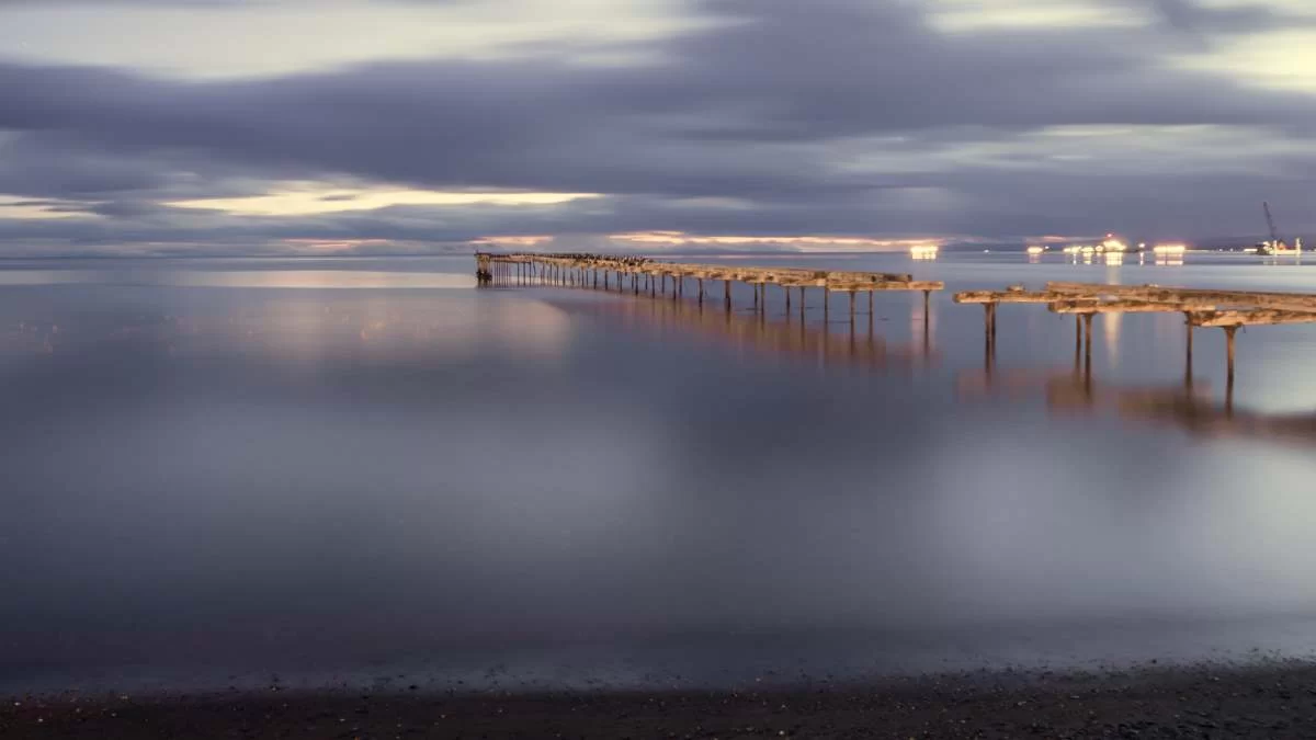 Παλαιά ξύλινη αποβάθρα στην Punta Arenas στη Χιλή στον Ειρηνικό Ωκεανό κατά τη δύση του ηλίου